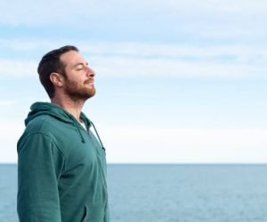 Relaxed man breathing fresh air with the sea at the background.